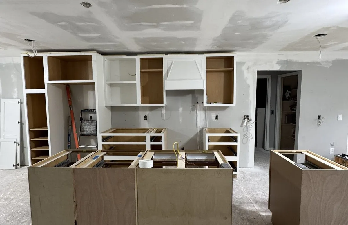 A kitchen mid install, with cabinet boxes set and the island framed