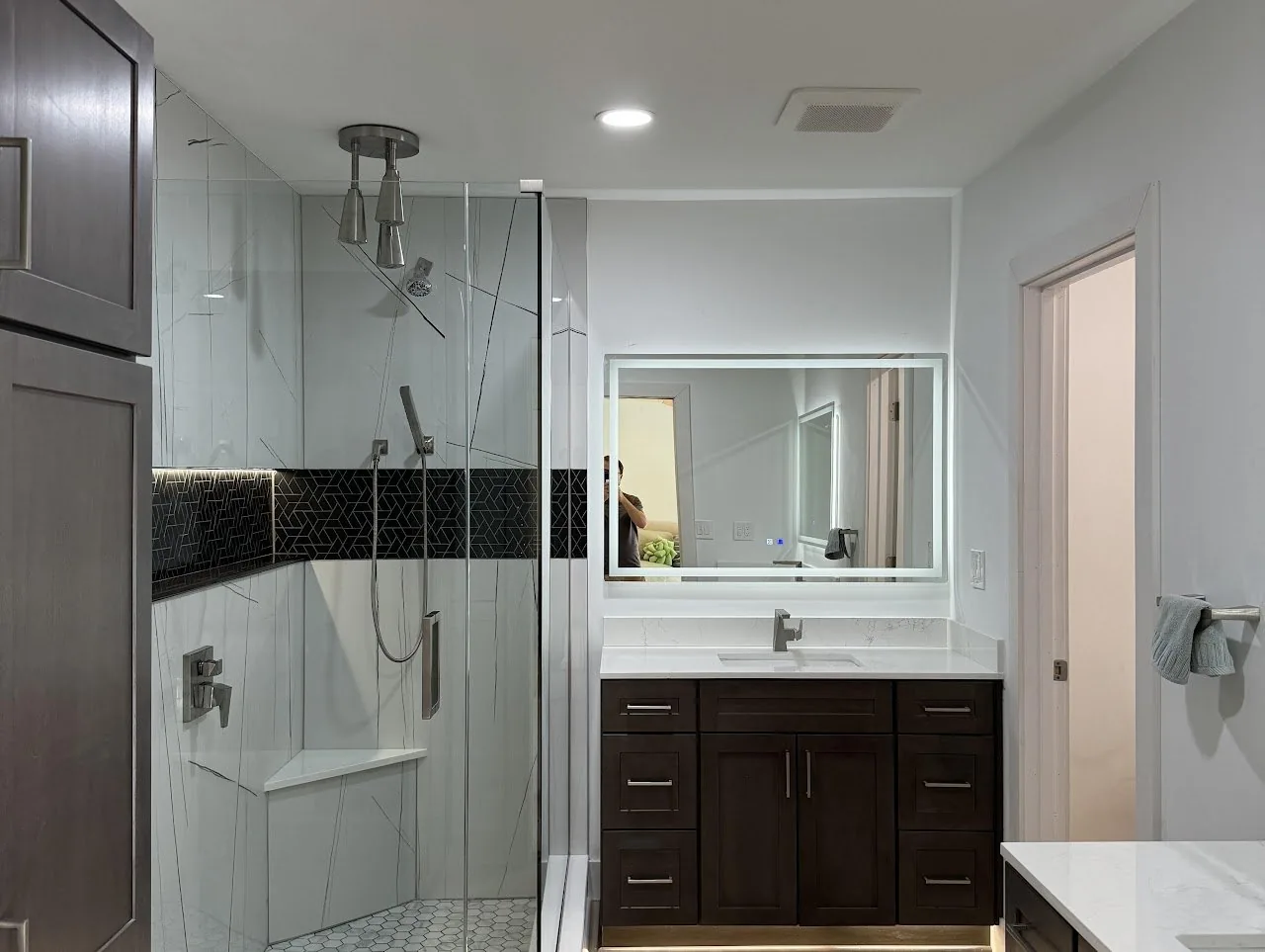 Bathroom with a glass shower, dark mosaic accent band and a dark wood vanity