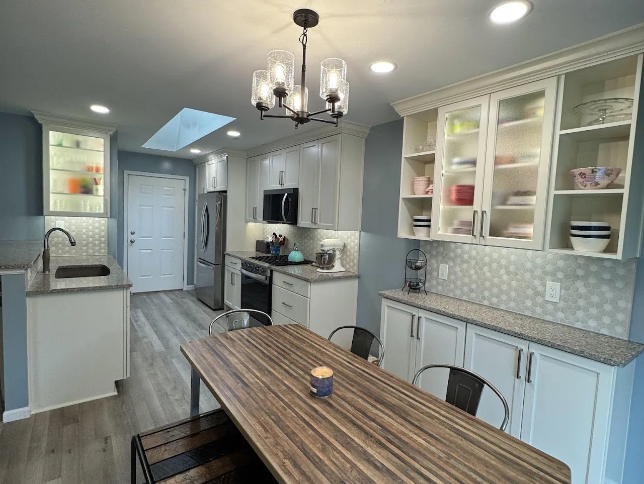 White kitchen with glass front cabinet doors, in cabinet lighting and a coffee bar