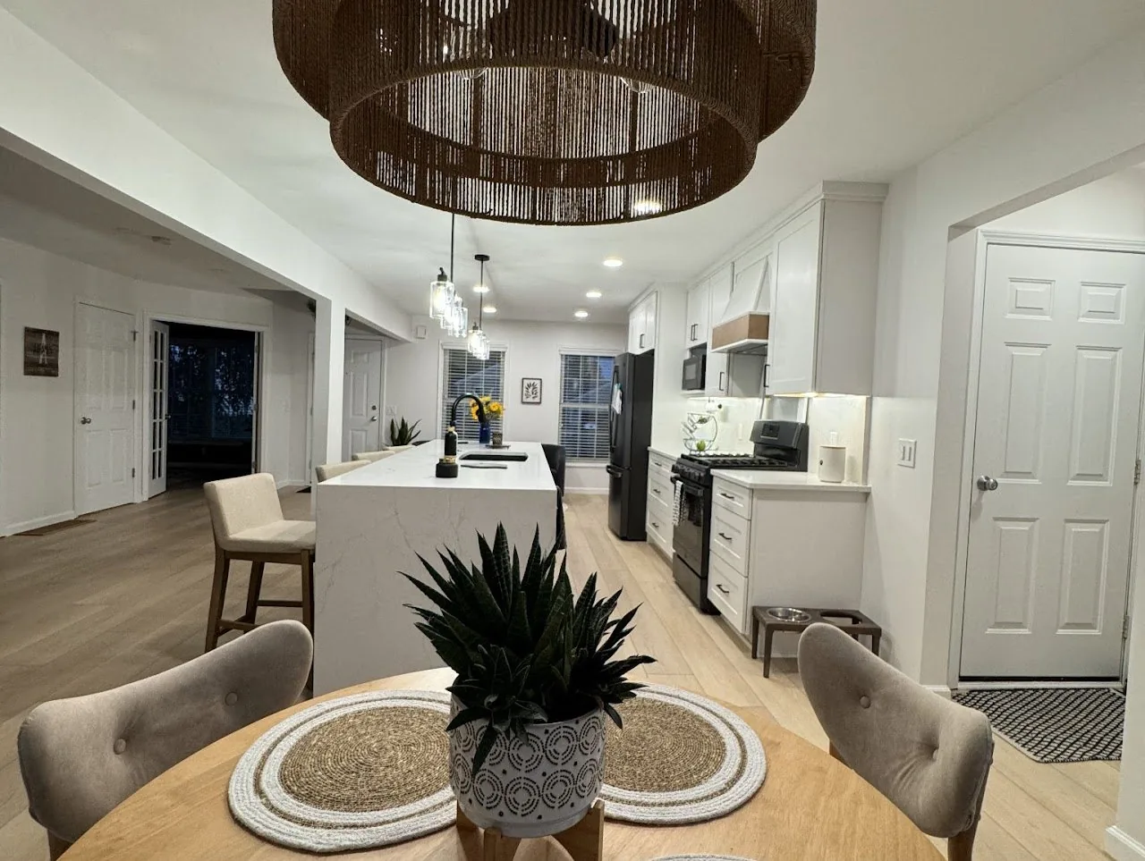 Open kitchen and dining room with a woven drum chandelier and a white island